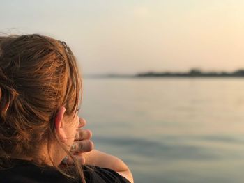 Rear view of woman looking at lake against sky