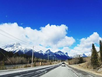 Road by mountains against blue sky