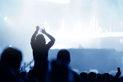 Rear view of silhouette of crowd with arms outstretched at concert. summer music festival concept