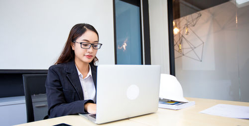 Portrait of young businesswoman using laptop at office