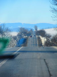 Road by trees against clear sky