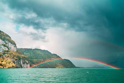 Scenic view of rainbow over sea against sky