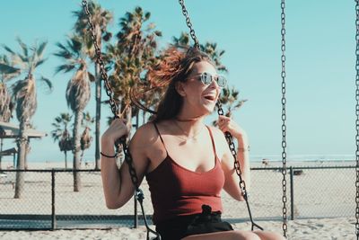 Young woman wearing sunglasses standing against clear sky