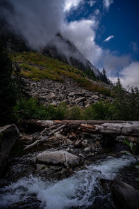 Stream flowing through rocks against sky