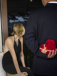 Rear view of man with gift standing against woman in ceremony