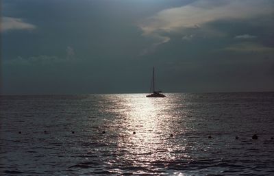 Silhouette sailboat sailing on sea against sky