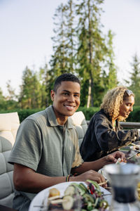 Portrait of smiling man sitting with female friend while having dinner at party