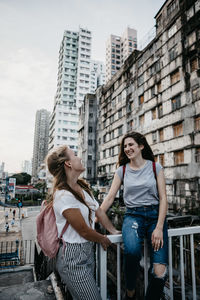 Full length of happy woman standing against buildings in city