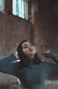 Portrait of young woman against wall