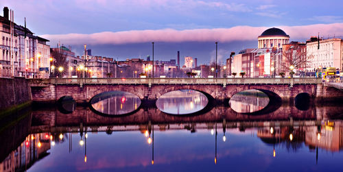 Arch bridge over river against sky in city