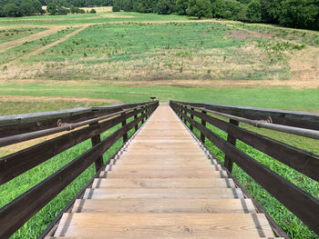 View of wooden footbridge on field