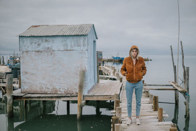 Portrait of young woman standing by river against sky