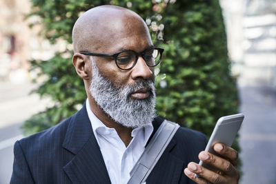 Mature businessman reading smartphone messages on the move