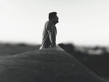 Side view of man leaning against railing