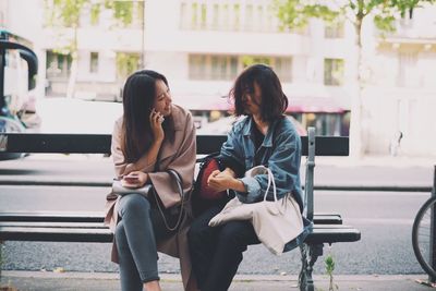 Friends sitting on bench against road