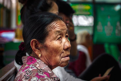 Side view of wrinkled senior woman sitting at home