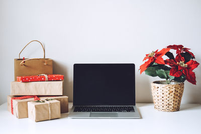 Blank display screen laptop computer with poinsettias christmas flower and gift boxes on white