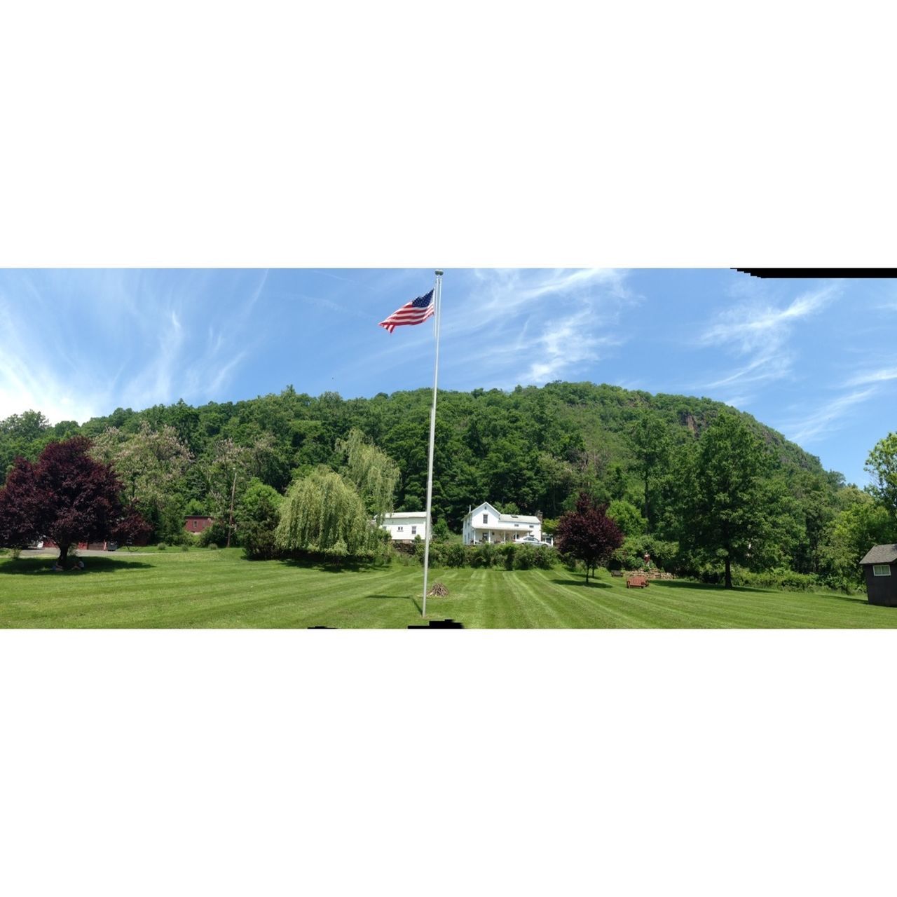 tree, sky, road, transfer print, flag, transportation, cloud, landscape, mountain, clear sky, nature, day, grass, patriotism, scenics, flying, blue, cloud - sky, sunlight, tranquility