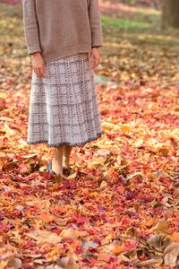 Low section of woman standing on autumn leaves