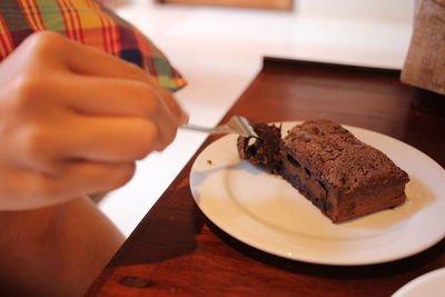 Close-up of hand having dessert in plate on table