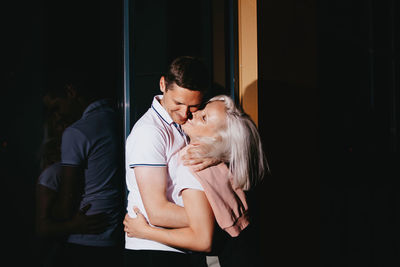 Couple embracing against glass window at night
