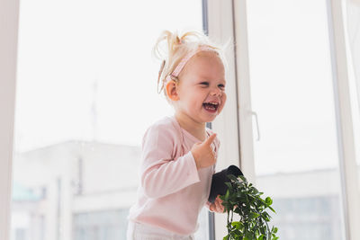 Portrait of smiling young woman holding christmas tree at home