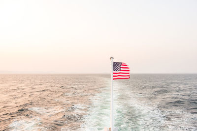 Flag on sea against clear sky