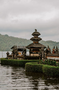 Buildings by river against sky