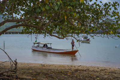 Fishing boat moored on beach against sky