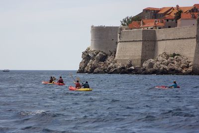 People on sea kayaking against sky