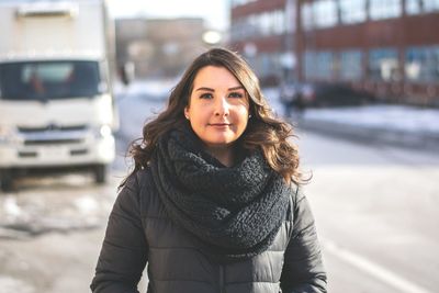 Portrait of smiling woman standing in city during winter