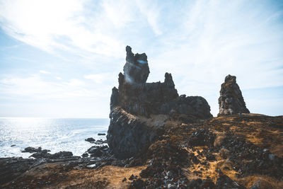 Rock formation on beach against sky