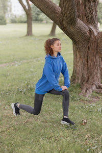 Full length of young woman exercising on field