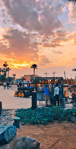 People at beach against sky during sunset