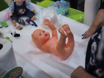 Midsection of woman changing doll diaper at home