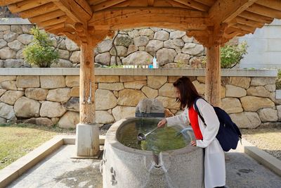 Woman holding umbrella while standing against wall