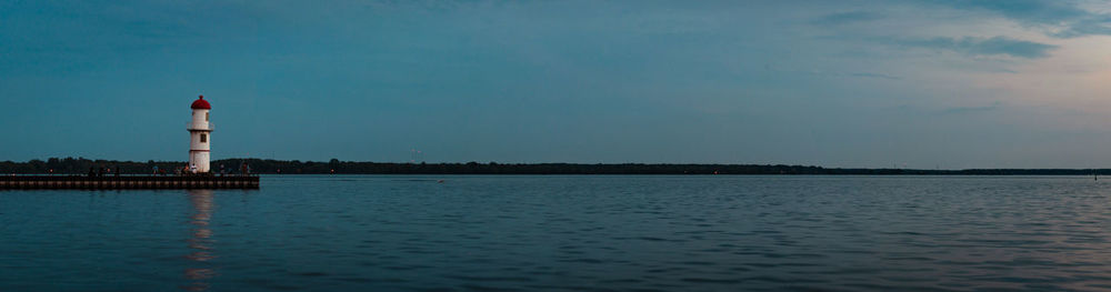 Lighthouse by sea against sky