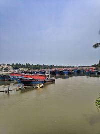 Boats moored at harbor against sky