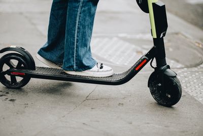 Low section of person riding skateboarding on street