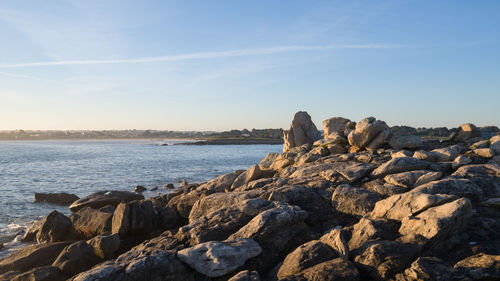 Rocks on shore by sea against sky