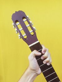 Midsection of man playing guitar against yellow background