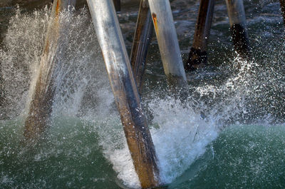 High angle view of waves splashing on poles in sea