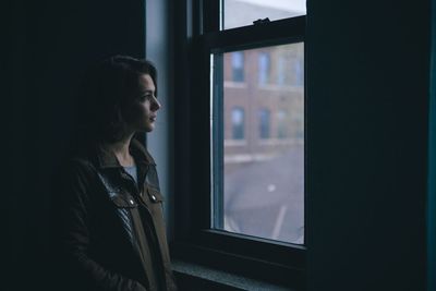Side view of woman looking towards window in apartment