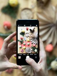 Close-up of the hand of an unknown woman who takes a photo of the new year's decor on the phone