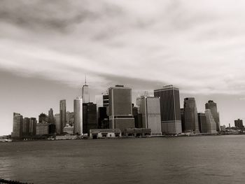 City at waterfront against cloudy sky