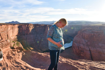 Pregnant woman standing on mountain against sky