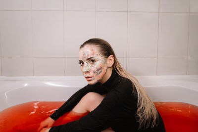 Portrait of young woman sitting in bathroom