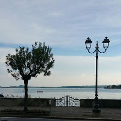 Street light by sea against sky