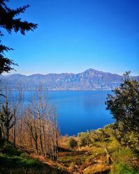 Scenic view of lake and mountains against clear blue sky
