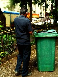 Rear view of man standing by garbage bin